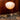 Round akari 10A wash paper japanese floor lamp with a warm glow on a tripod stand against a wooden wall.