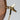 Wooden mirror with a gold metal handle on a light gray background