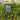 Decorative garden light with verdigris shade in a garden setting with yellow flowers.