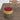 Multicolored ottoman on a brown carpet with a wooden chair in the background.