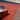 Stack of books and a bowl on a multicolored rug with a wooden floor.