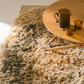 Shaggy beige ochre 70s style rug with a wooden coffee table and glasses on it.