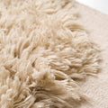 Close-up of a beige shaggy rug with a soft texture.