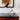 Black and gold desk lamp on a wooden surface with abstract art in the background