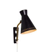 Black wall-mounted midcentury diabolo shaped lamp with plug and brass arm by Mauri Almari on a white background