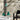 Green pendant lights on a marble table with a black chair against a textured wall.