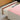 Open drawer with pink top section and wooden sides on a light wood floor.