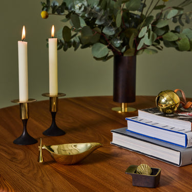 Decorative setup with candles, books, and a vase on a wooden table.