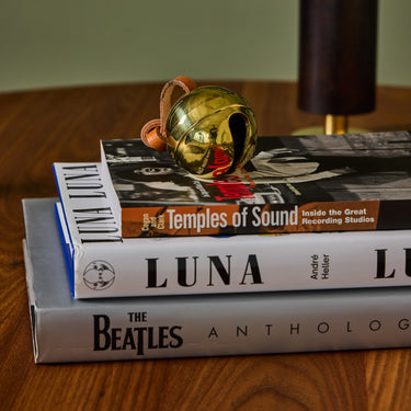 brass jingle bell paperweight on stack of books