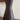 Dark brown ceramic vase with wooden sticks on a reflective surface