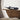 Decorative whale sculpture on a wooden shelf with a concrete wall background