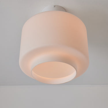 Ceiling light fixture with a white glass shade on a plain background