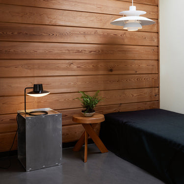 AJ oxford table lamp louis poulsen in a wood room on a steel plinth with a chapo sfax stool