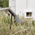 Modern outdoor pathway light in a grassy area with a white building in the background