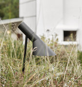 Modern outdoor pathway light in a grassy area with a white building in the background