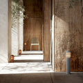Modern outdoor setting with a wooden wall, tiled floor, and a chair with pathway lighting