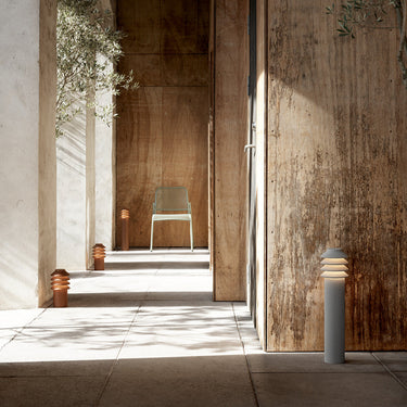 Modern outdoor setting with a wooden wall, tiled floor, and a chair with pathway lighting