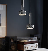 Vintage record player on a wooden cabinet with dark wall and hanging chrome VL56 pendant lights.