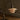 A modern table lamp with a dark metal gooseneck and layered translucent shades in a warm cream color, shown lit on a wooden tabletop.