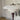 A close-up of a modern table lamp with a glossy white tiered dome shade and a dark burgundy metal base, set against a softly blurred indoor background.