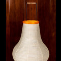 White washi paper lampshade with an orange rim and black metal stand against a wooden background