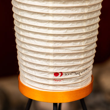 White paper lantern with orange base on a blurred background noguchi stamp visible