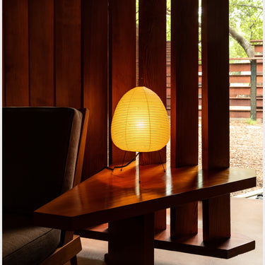 Akari 1A lamp on a wooden table with a dark curtain background at schaffer lautner house whiting woods