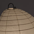 Beige paper lantern with black wire frame on a dark background
