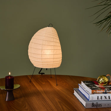 Akari 1N washi paper Table lamp on a wooden surface with candles and books against a green wall