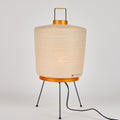 Table lamp with beige shade and black metal legs on a white background