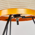 Close-up of a lamp with wooden base and metal legs on a plain background