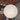 A large spherical pendant light made of textured cream paper or fabric, suspended from a ceiling in an indoor room with exposed wooden beams and wood paneling.