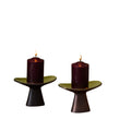 Two purple candles on small stands against a plain background