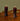 Two purple candles on black holders on a wooden table with a green wall background