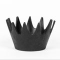 Black metal crown-shaped object on a white background
