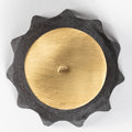 Decorative object with gold center and black textured rim on a white background