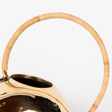 brass watering can with a wicker handle on a white background
