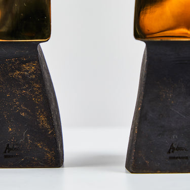 Two brass bookends with a textured surface on a white background