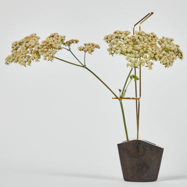 vase sculpture with white flowers in a rustic pot on a light gray background