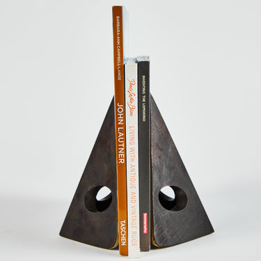 Triangular bookend holding books on a white background
