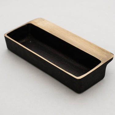 Black rectangular brass dish with brass sides on a light gray background
