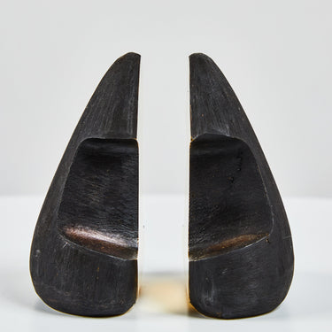 Two black brass bookends on a white background