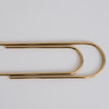 Gold paper clip on a white background