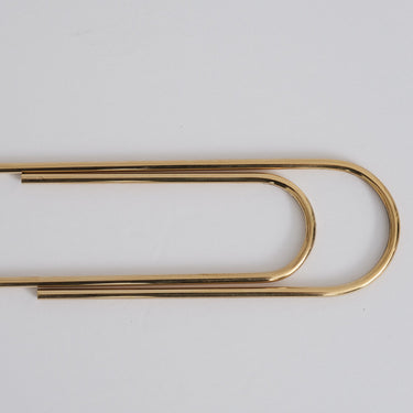 Gold paper clip on a white background