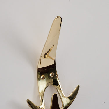 Gold-colored wall hook on a light gray background