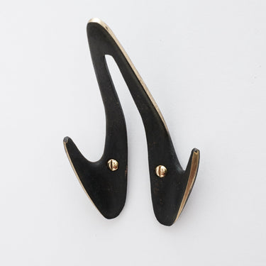 blackened brass wall hook on a light gray background