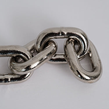 Close-up of a metal chain link paperweight on a light gray background