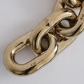 Close-up of a gold chain link paperweight on a light gray background