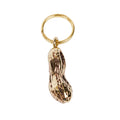Gold keychain shaped like a peanut on a white background