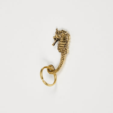 Gold seahorse-shaped keychain on a white background